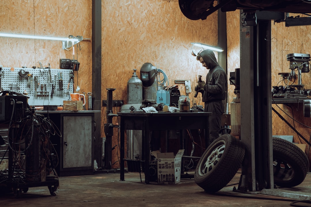 Mechanic working under a vehicle on a lift at an auto repair shop — auto repair shop insurance FAQ