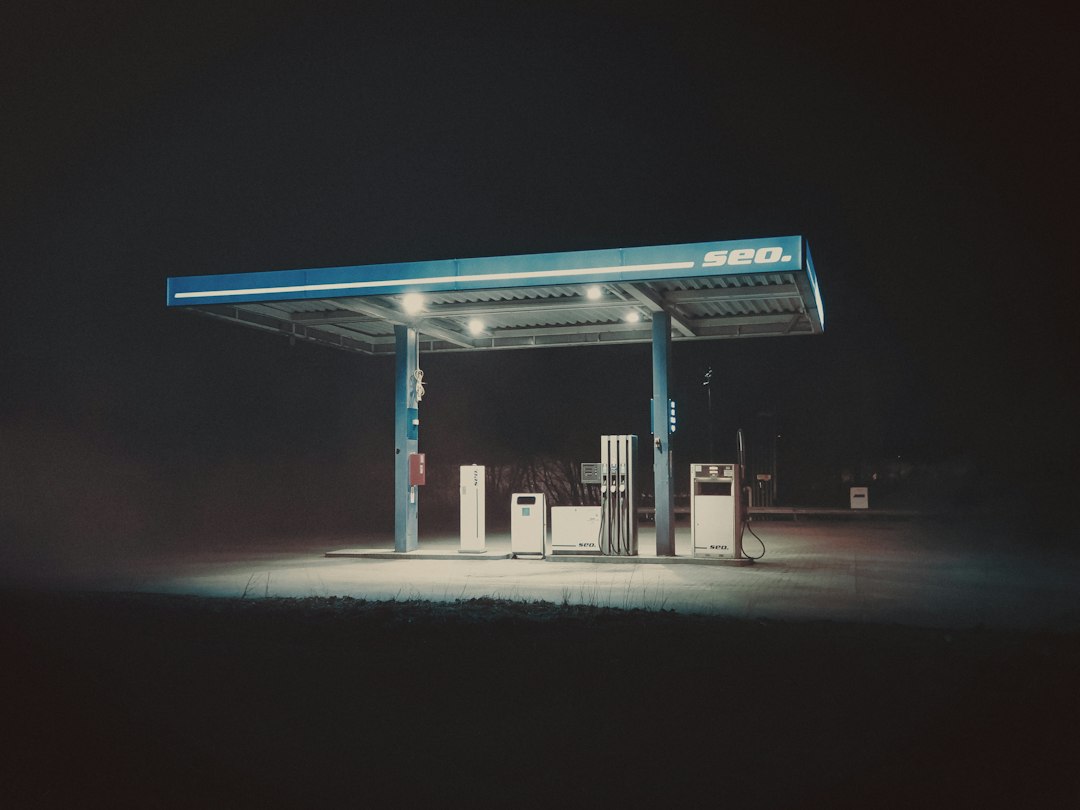Fuel pumps under a lighted canopy at a fuel station convenience store